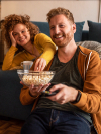 una pareja mirando TV mientras comen palomitas de maíz
